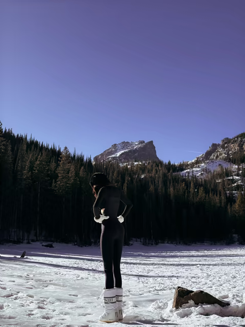A hiker looking toward a snowy mountain above a frozen lake